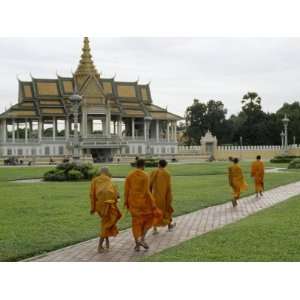  Buddhist Monks in Orange Robes Walk Through a Park with a 